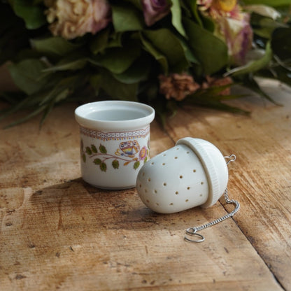 Boule à thé "Mancielle" en porcelaine fleurie et son support en porcelaine de Paris