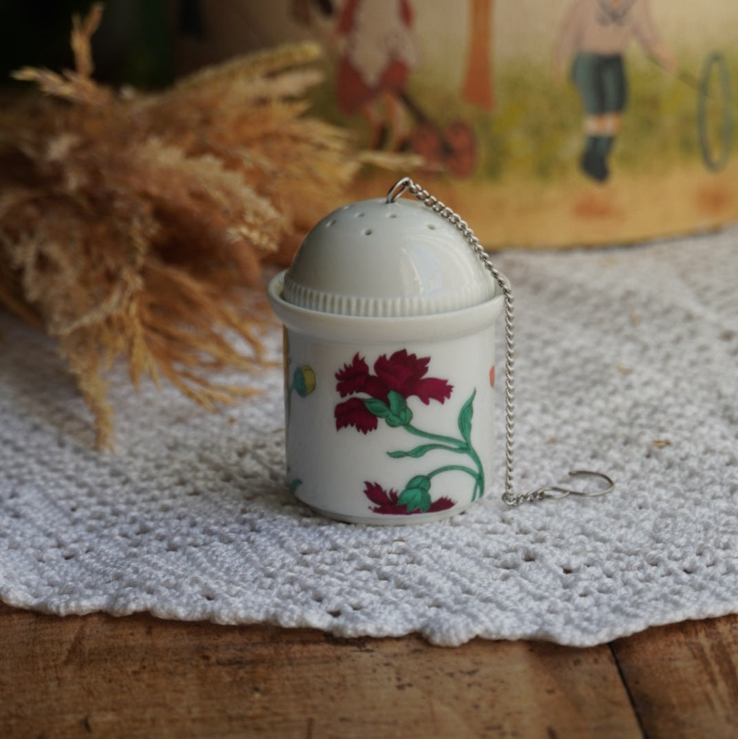 Boule à thé "Nalidée" en porcelaine fleurie et son support en porcelaine de Paris décor Herbier