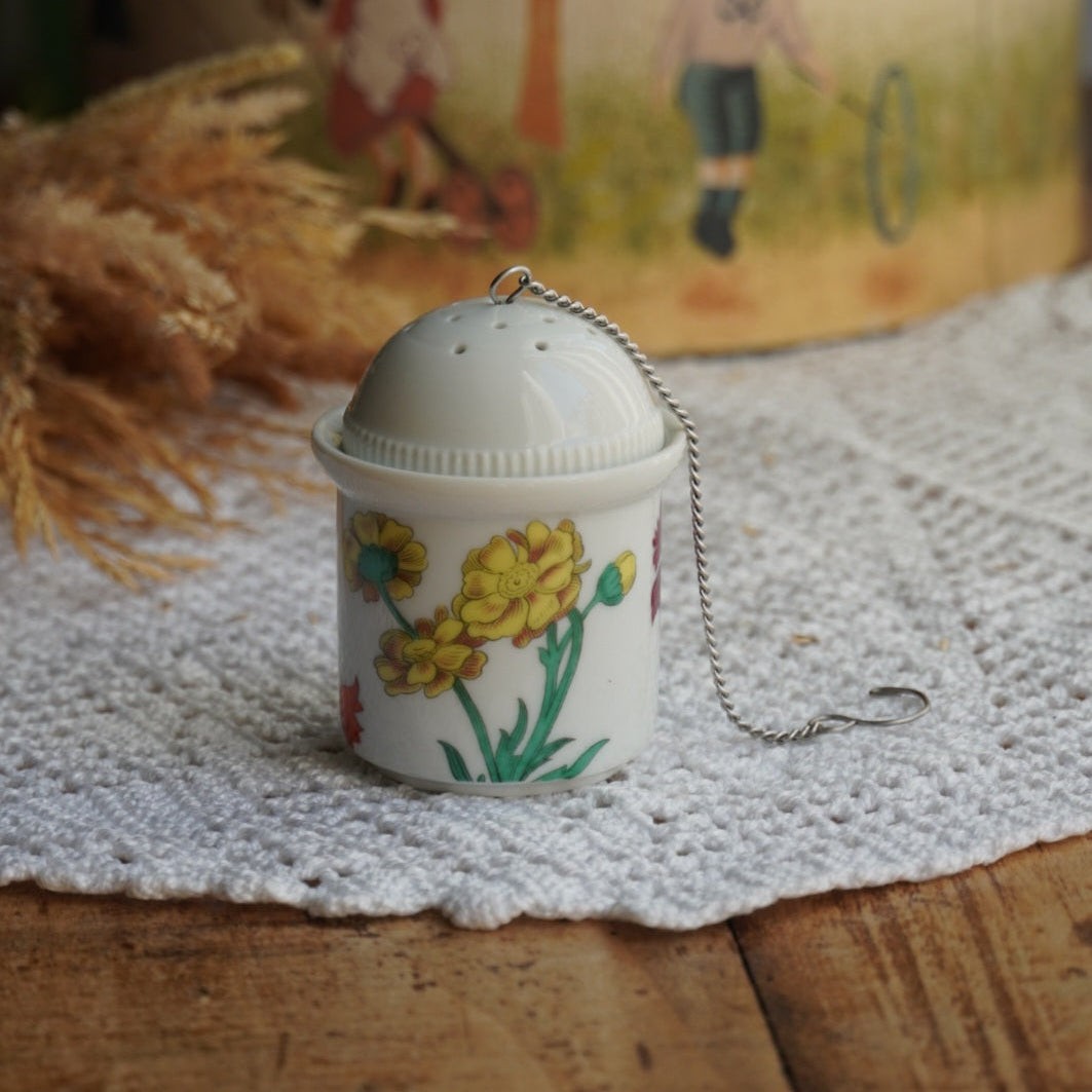 Boule à thé "Nalidée" en porcelaine fleurie et son support en porcelaine de Paris décor Herbier
