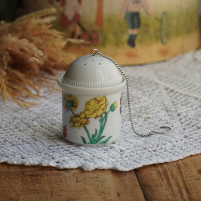 Boule à thé "Nalidée" en porcelaine fleurie et son support en porcelaine de Paris décor Herbier