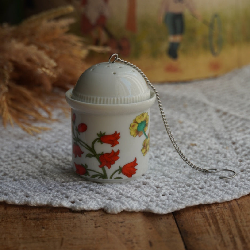 Boule à thé "Nalidée" en porcelaine fleurie et son support en porcelaine de Paris décor Herbier