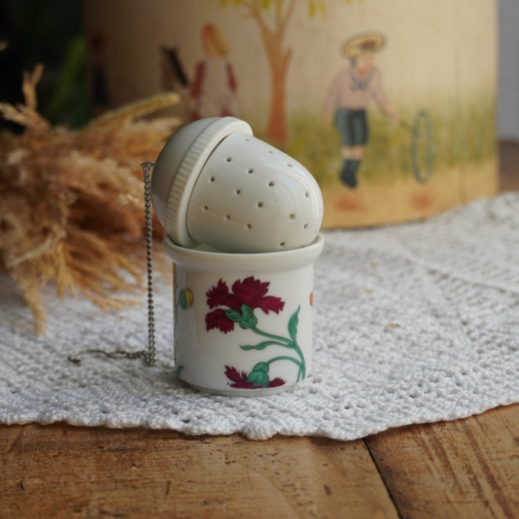 Boule à thé "Nalidée" en porcelaine fleurie et son support en porcelaine de Paris décor Herbier