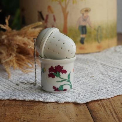 Boule à thé "Nalidée" en porcelaine fleurie et son support en porcelaine de Paris décor Herbier