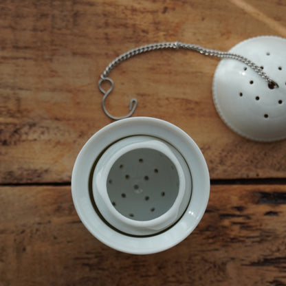 Boule à thé "Nalidée" en porcelaine fleurie et son support en porcelaine de Paris décor Herbier