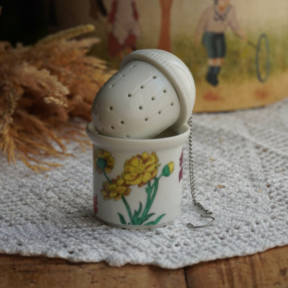 Boule à thé "Nalidée" en porcelaine fleurie et son support en porcelaine de Paris décor Herbier