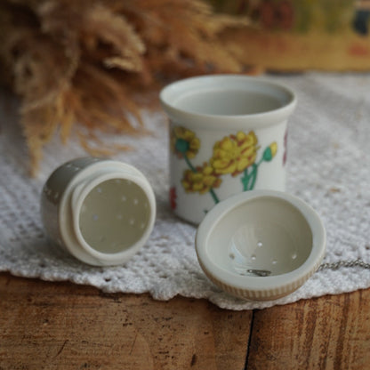 Boule à thé "Nalidée" en porcelaine fleurie et son support en porcelaine de Paris décor Herbier