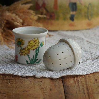 Boule à thé "Nalidée" en porcelaine fleurie et son support en porcelaine de Paris décor Herbier